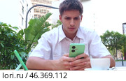 Young man in cafe looking at phone and shaking head in disapproval. Стоковое видео, видеограф Raquel Corcoles Mendez / Фотобанк Лори