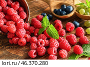Overturned bowl with ripe raspberries on wooden table. Стоковое фото, фотограф Pixel_shot / Фотобанк Лори