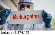 Doctor holding a banner with text Marburg Virus sign. Scientist in protective gear, gloves and medical mask. New epidemic illness. Outbreak of infectious disease spreading, worldwide pandemic. Стоковое AI-видео, аниматор Марина Демидюк / Фотобанк Лори