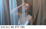 Slow motion video of young female covered with veil. Woman is dressed in a peignoir and wears a necklace and earrings. Стоковое видео, видеограф Сергей Пристяжнюк (Serg Zastavkin) / Фотобанк Лори