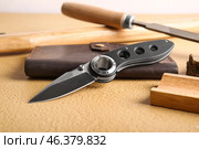 Folding pocket knife with rubberized handle on table. Стоковое фото, фотограф Pixel_shot / Фотобанк Лори
