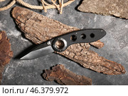 Folding pocket knife with rubberized handle and tree barks on textured background. Стоковое фото, фотограф Pixel_shot / Фотобанк Лори