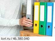 Man putting folder with documents on shelf in office. Стоковое фото, фотограф Pixel_shot / Фотобанк Лори