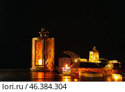 Arabic candle holder with glowing fanoos lamps and Quran on dark background. Стоковое фото, фотограф Pixel_shot / Фотобанк Лори