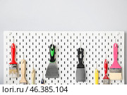 Pegboard with putty knives and brushes on light wall. Стоковое фото, фотограф Pixel_shot / Фотобанк Лори