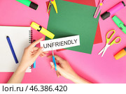 Woman with scissors turning word UNFRIENDLY to FRIENDLY on color background. Стоковое фото, фотограф Pixel_shot / Фотобанк Лори