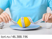 Woman with plate, lemon and measuring tape at table. Concept of anorexia. Стоковое фото, фотограф Pixel_shot / Фотобанк Лори