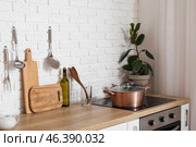 Wooden counters with cutting boards, utensils, houseplant and electric stove in modern kitchen. Стоковое фото, фотограф Pixel_shot / Фотобанк Лори