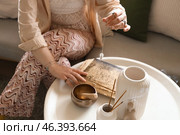 Young witch with pendulum and spell book on table at home, closeup. Стоковое фото, фотограф Pixel_shot / Фотобанк Лори