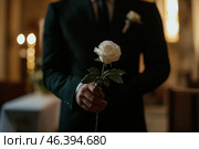 Мужчина в черном костюме держит белую розу на фоне свадебного алтаря. Шаблон концепции жениха, ожидающего невесту. Стоковое AI-изображение, AI-художник Екатерина Селезнева / Фотобанк Лори