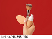 Hand with makeup sponge, concealer and brush on color background. Стоковое фото, фотограф Pixel_shot / Фотобанк Лори