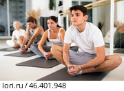 Young man practicing pilates on gray mat in gym room. Стоковое фото, фотограф Яков Филимонов / Фотобанк Лори