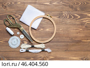 Embroidery hoop with canvas, scissors and mouline threads on brown wooden background. Стоковое фото, фотограф Pixel_shot / Фотобанк Лори