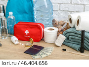 Necessities for emergency bag on wooden table near white brick wall. Стоковое фото, фотограф Pixel_shot / Фотобанк Лори