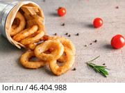 Overturned bucket with tasty onion rings on table. Стоковое фото, фотограф Pixel_shot / Фотобанк Лори