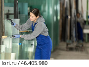 Girl glazer employee in blue overall works in glass processing shop. Стоковое фото, фотограф Яков Филимонов / Фотобанк Лори