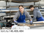 Girl glazer employee in blue overall works in glass processing shop. Стоковое фото, фотограф Яков Филимонов / Фотобанк Лори