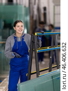 Girl glazer employee in blue overall works in glass processing shop. Стоковое фото, фотограф Яков Филимонов / Фотобанк Лори