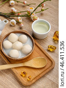 Bowl of tangyuan with cup, Chinese decor and sakura on wooden background. Dongzhi Festival. Стоковое фото, фотограф Pixel_shot / Фотобанк Лори