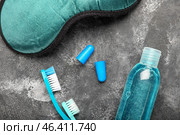 Earplugs, toothbrushes, sleeping mask and bottle of cosmetic product on dark background. Стоковое фото, фотограф Pixel_shot / Фотобанк Лори
