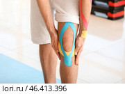 Sporty man with physio tape applied on knee in gym, closeup. Стоковое фото, фотограф Pixel_shot / Фотобанк Лори