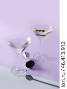 Glasses of martini with olives, bar spoon and jigger on color background. Стоковое фото, фотограф Pixel_shot / Фотобанк Лори