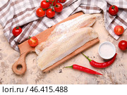Wooden board with raw codfish fillet and tomatoes on beige background. Стоковое фото, фотограф Pixel_shot / Фотобанк Лори