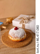 Stand with tasty doughnut for Hannukah celebration on table near beige wall, closeup. Стоковое фото, фотограф Pixel_shot / Фотобанк Лори