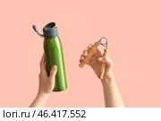 Female hands with sport bottle of water and expander on pink background. Стоковое фото, фотограф Pixel_shot / Фотобанк Лори