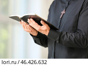 Male priest with Bible at home, closeup. Стоковое фото, фотограф Pixel_shot / Фотобанк Лори