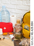 Necessities for emergency bag on wooden table near white brick wall. Стоковое фото, фотограф Pixel_shot / Фотобанк Лори