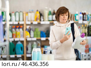 Woman client scans QR code on package and downloads promo code to purchase liquid detergent. Стоковое фото, фотограф Яков Филимонов / Фотобанк Лори