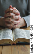 Person is praying with their hands on their lap in front of a Bible. Стоковое AI-видео, аниматор Sergey Grishin / Фотобанк Лори