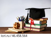 Минометная доска, диплом, канцелярские товары и книги на столе. Концепция окончания средней школы. Стоковое фото, фотограф Pixel_shot / Фотобанк Лори