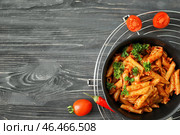 Сковорода с вкусной пастой пенне и томатным соусом на деревянном столе. Стоковое фото, фотограф Pixel_shot / Фотобанк Лори