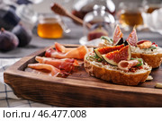 Вкусные бутерброды со спелым инжиром и прошутто на деревянной доске. Стоковое фото, фотограф Pixel_shot / Фотобанк Лори