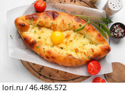 Деревянная доска вкусных хачапури по-аджарски на белом фоне крупным планом. Стоковое фото, фотограф Pixel_shot / Фотобанк Лори