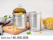 Жестяные банки, миска с кукурузными зернами, разделочная доска и салфетка на сером столе. Стоковое фото, фотограф Pixel_shot / Фотобанк Лори