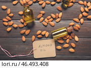 Бутылки миндального масла, торговых ярлыков и орехов на деревянном фоне. Стоковое фото, фотограф Pixel_shot / Фотобанк Лори
