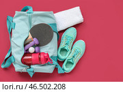 Спортивная сумка с спортивной одеждой, водой и оборудованием для пинг-понга на красном фоне. Стоковое фото, фотограф Pixel_shot / Фотобанк Лори