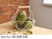 Корзина с вкусными сырыми артишоками на деревянном столе. Стоковое фото, фотограф Pixel_shot / Фотобанк Лори