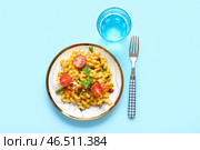 Тарелка с вкусной пастой примавера и стакан воды на голубом фоне. Стоковое фото, фотограф Pixel_shot / Фотобанк Лори
