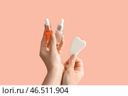 Женские руки, держащие косметические продукты и массажер для лица гуа ша на розовом фоне. Стоковое фото, фотограф Pixel_shot / Фотобанк Лори