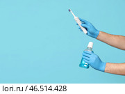 Мужчина-стоматолог с электрической зубной щеткой и бутылкой полоскания для полости рта на голубом фоне. Всемирный день стоматолога. Стоковое фото, фотограф Pixel_shot / Фотобанк Лори