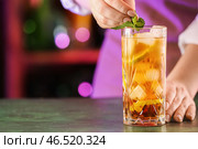Женщина-бармен кладет мяту в стакан вкусного коктейля Cuba Libre на стол в баре. Стоковое фото, фотограф Pixel_shot / Фотобанк Лори