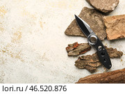 Складной карманный нож с прорезиненной рукоятью, лежащий на камнях и коре деревьев. Стоковое фото, фотограф Pixel_shot / Фотобанк Лори