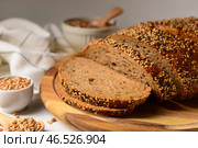 Деревянная доска с нарезанным батоном хлеба и зернами пшеницы на белом столе. Стоковое фото, фотограф Pixel_shot / Фотобанк Лори