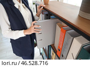 Молодая бизнесвумен берет папку с документами с полки в офисе, крупный план. Стоковое фото, фотограф Pixel_shot / Фотобанк Лори