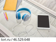 Наушники с планшетным ПК и канцелярские принадлежности на стеклянном столе. Стоковое фото, фотограф Pixel_shot / Фотобанк Лори