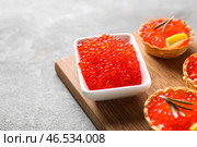 Чаша с вкусной красной икрой и канапе на деревянной доске, крупным планом. Стоковое фото, фотограф Pixel_shot / Фотобанк Лори